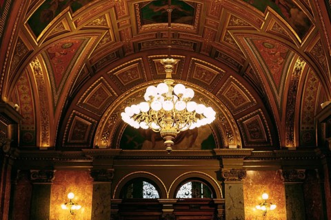 Large golden chandelier under the gilded ceiling in the interior.