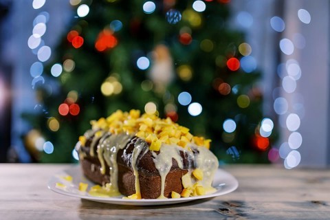 Christmas stollen stands on a plate on a wooden table.