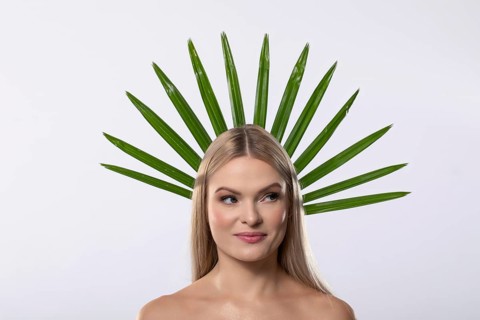A creative portrait of a woman adorned with vibrant green leaves, symbolizing harmony between