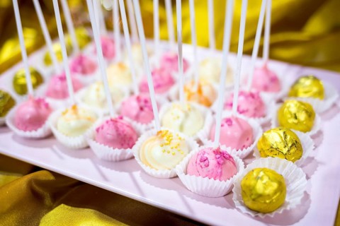 Different colourful candies on a stick. Bonbons wrapped in golden foil. Yellow, pink, white.