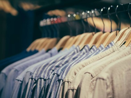 Close up view of man clothes hang in clothes store. Hangers with different male clothes. Copy space