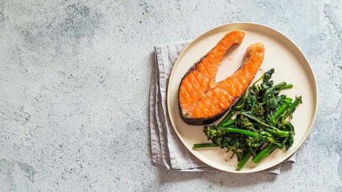 Ready-to-eat grilled salmon steak and greens - baby broccoli or broccolini and spinach on rustic