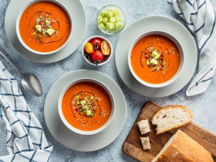Gaspacho soup on white marble tabletop. Three bowls of traditional spanish cold soup puree gaspacho
