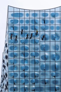 People working as window cleaners on the striking glass façade of a tall building, Elbphilharmonie,