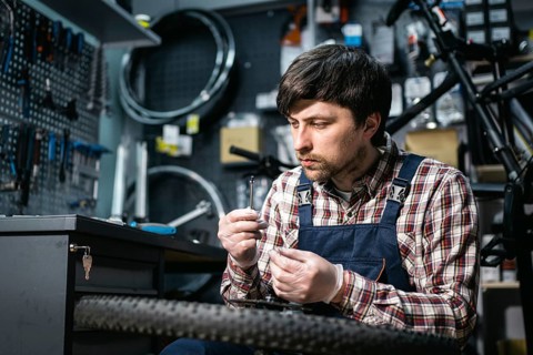 Bicycle mechanic fixing cycle wheel in repair shop. Velocipede service. Repairer male bike shop
