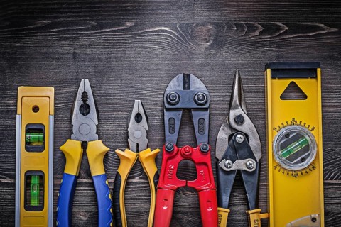 Tin snips steel cutter pliers construction level on wooden board