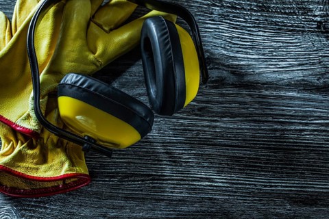 Protective earmuffs leather gloves on wooden board