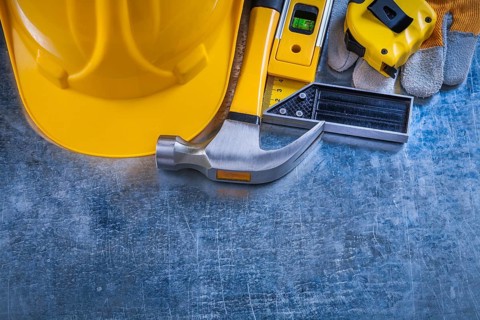 Safety gloves try square construction level tape-line hard hat and claw hammer on metallic