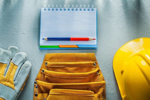 Protective gloves building helmet notebook pencil tool belt on concrete background