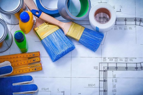 Wooden meter household tapes safety gloves and paint tools on blueprint maintenance concept