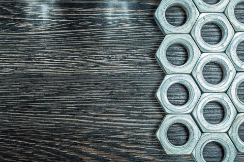 Stainless construction nuts on wooden board