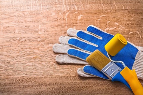 Protective gloves paint roller and brush on wooden board construction concept