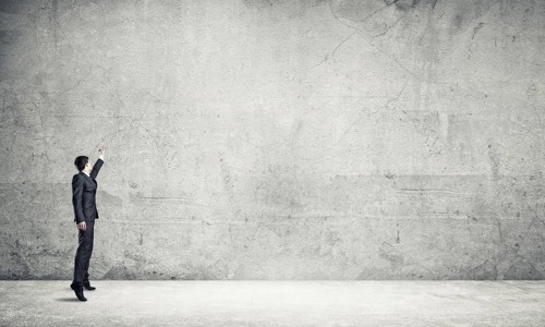 Businessman in empty concrete room drawing on wall
