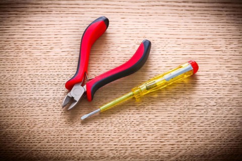 Electrical tester and pliers on wooden board