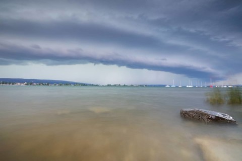 Gloomy mood with boats on the horizon under a cloudy, grey sky with a shelf cloud, Allensbach,