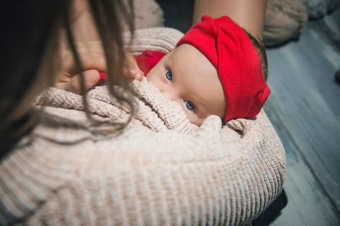 Loving Mother Cuddling Sleeping Newborn Baby daughter Over Shoulder