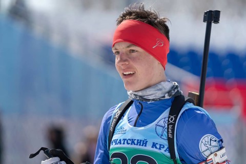Portrait of sportsman biathlete Sporshev Nikita at finish after rifle shooting and skiing. Junior