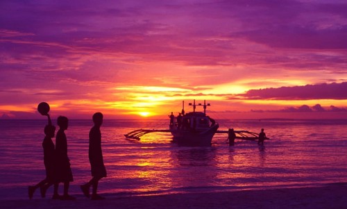 Philippines: Three local football boys walking on the beach on the island of Boracay