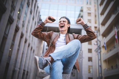 Man Sitting Listening Music Earphones Concept. Cheerful young guy listening the music