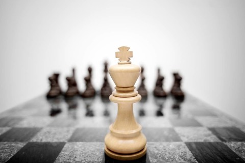 The expressive photo of the chess king standing in front of the set of pieces of a different colour