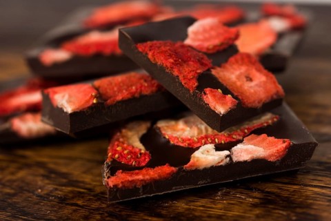 Stack of chocolate slices with strawberry on wooden background