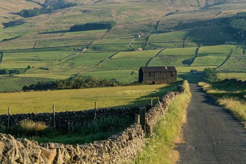A black barn on the side of a rural road in the Peak District between Rookhope and Ireshopeburn,
