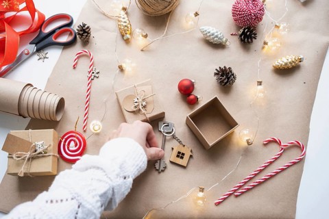 Key to house with keychain on cozy home in gift box with Christmas decor packaging. Pack present