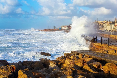 Huge stones protect the coast from huge storm waves. Powerful winter surf takes off with snow-white