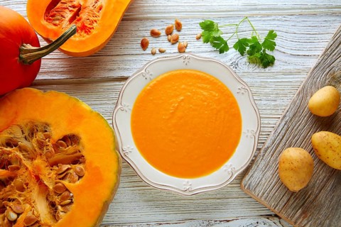 Pumpkin soup cream on a wooden table and ingredients