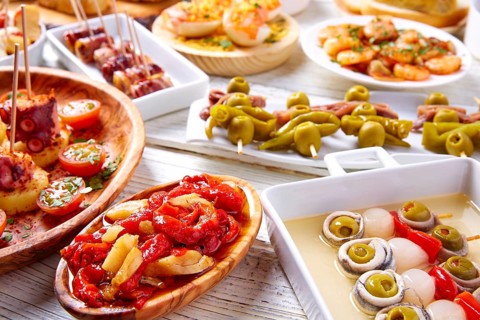 Tapas mix and pinchos food from Spain recipes also pintxos on a white wood board