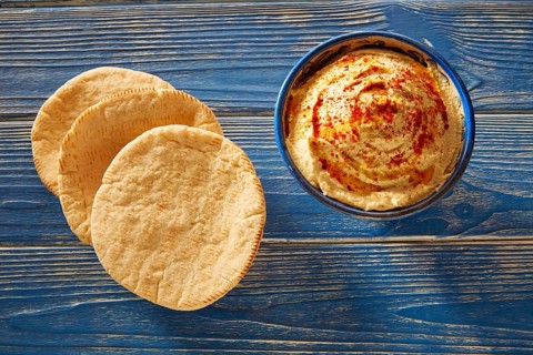 Hummus with pita bread and red pepper powder on blue Mediterranean wood table