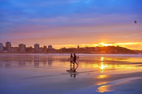 Gijon sunset San Lorenzo beach with surfers in Asturias of spain