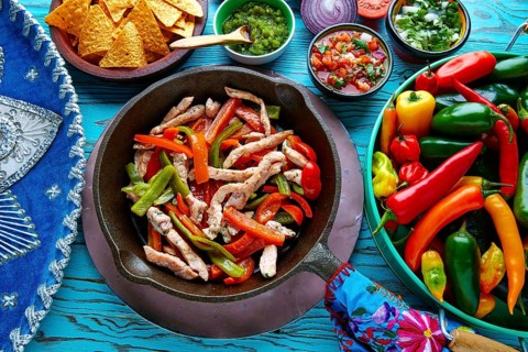 Chicken fajitas in a pan with sauces chili and sides Mexican food