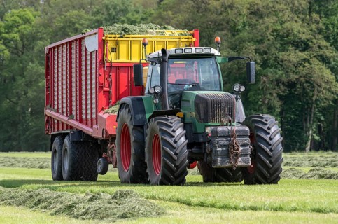 Picking up dried grass for silage with a green tractor and red loader wagon