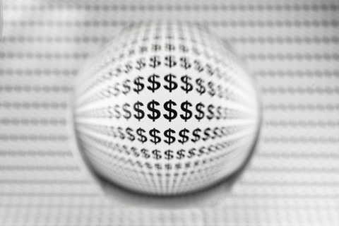 Studio shot of a glass sphere on a sheet of paper with dollar signs