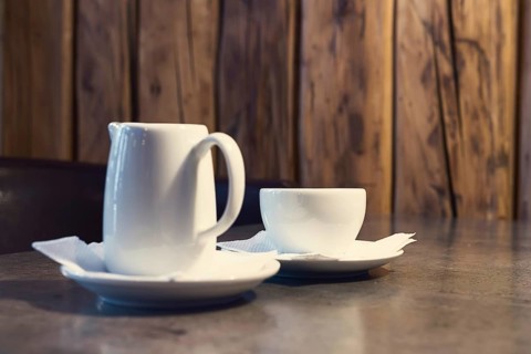Cappuccino coffee with milk. Cup of cappuccino and jug of milk on wooden background
