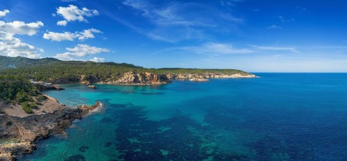Aerial view the green and rugged hilly coast of northern Ibiza with the turquoise waters of Cala