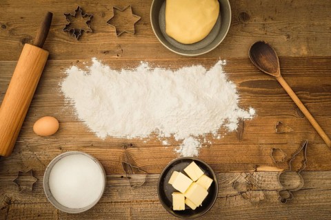 Collection of ingredients and utensils for baking Christmas biscuits with flour as text space in