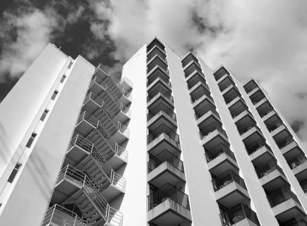Monochrome angled detail view of an old 1960s white concrete apartment building with steps and