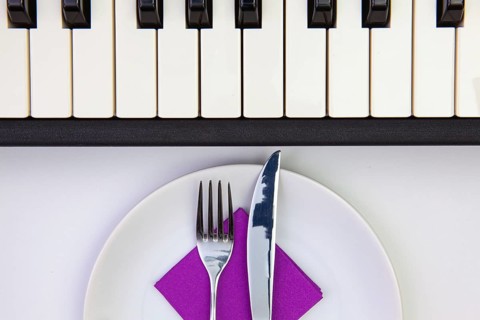 Symphony of taste. White plate and piano keys on the white wooden table.Top view. Flat Lay Image