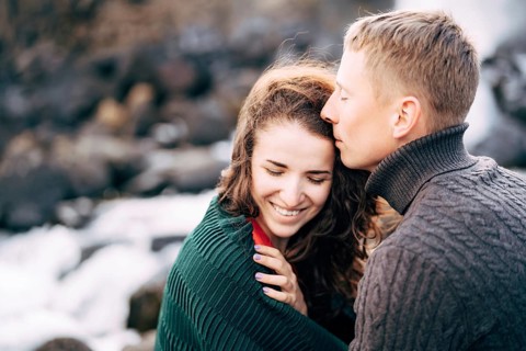 The guy hugs the girl, kisses her on the forehead. The girl smiles.