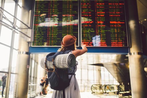Theme travel public transport. young woman standing back in dress and hat behind backpack camping