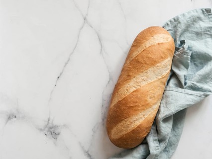 British White Bloomer or European Baton loaf bread on white marble background. Top view or flat lay