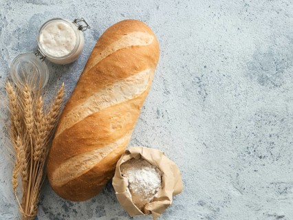 British White Bloomer or European sourdough Baton loaf bread on gray cement background. Fresh loaf