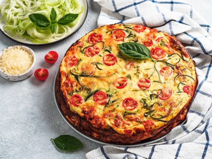 Zucchini pie and ingredients on gray background, copy space left. Delicious savory pie with