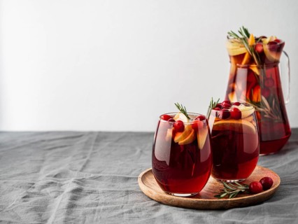 Winter sangria on tabletop with gray linen tablecloth. Jugful of sangria and glasses with with