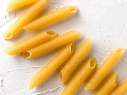 Raw pasta as food background. Italian Penne Rigate Macaroni Pasta on textured white background.