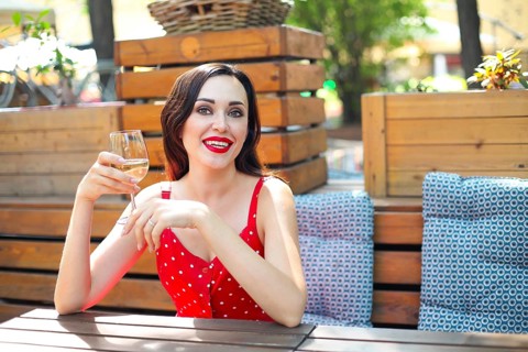 Close up portrait of brunette woman wearing polka dots dress having wine in a restaurant