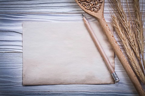 Bunch of wheat-rye ears wooden spoon corn pencil vintage paper on wood board