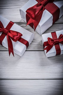 Present boxes with tied ribbons on wooden board holidays concept
